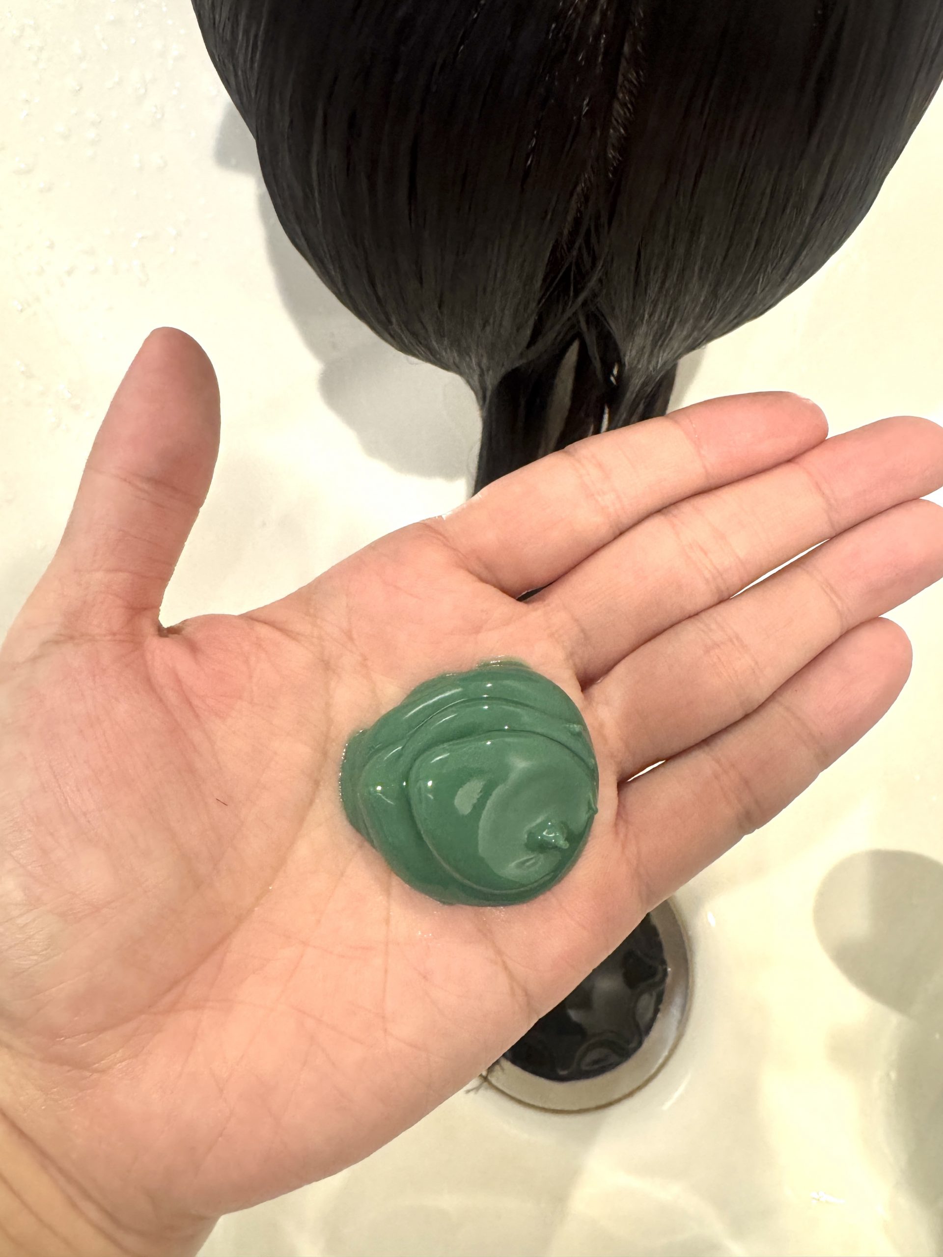 新処方の緑色のクリームを手のひらに乗せた写真。pH調整・内部結合強化・残留物除去などの新成分を含むトステア進化版の要素。